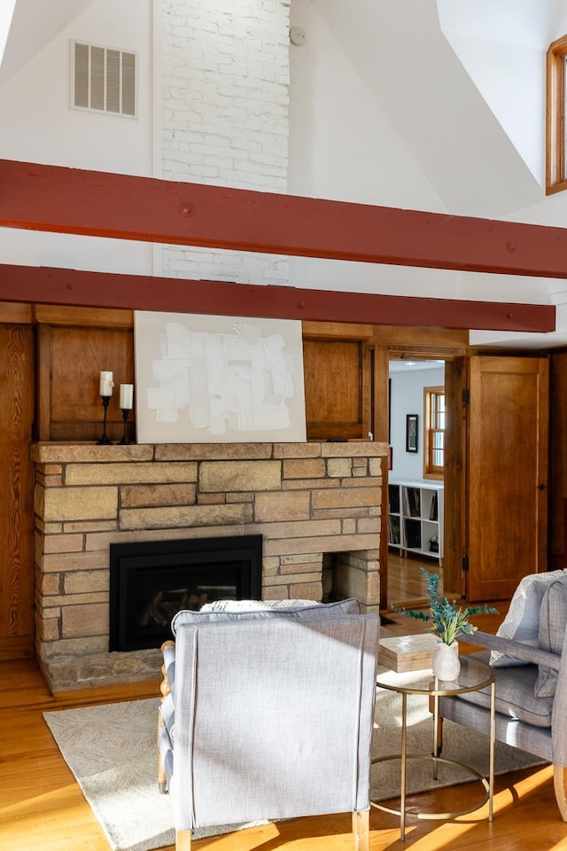 living room with visible vents, high vaulted ceiling, a stone fireplace, and light wood finished floors