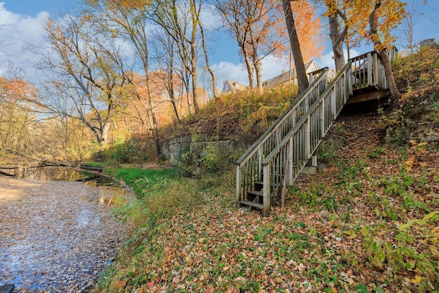 view of yard featuring driveway and stairs