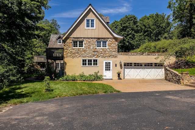 view of property exterior with board and batten siding, a yard, a garage, stone siding, and driveway