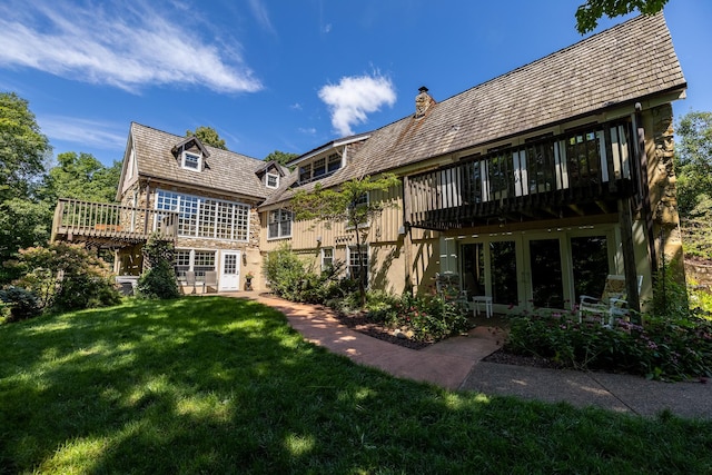 rear view of property featuring a chimney, a wooden deck, and a yard