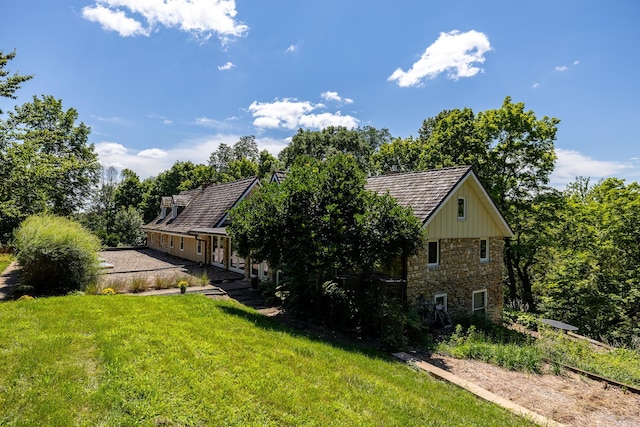 exterior space with stone siding and a lawn