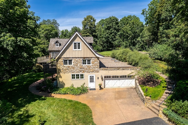 view of front of home featuring stone siding, board and batten siding, concrete driveway, a front yard, and a garage