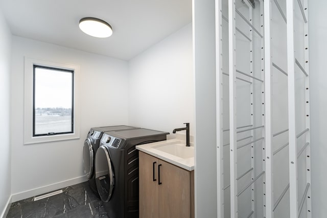 laundry room featuring sink, washing machine and dryer, and cabinets