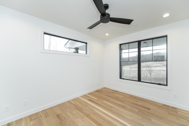 spare room featuring ceiling fan, light hardwood / wood-style flooring, and a wealth of natural light