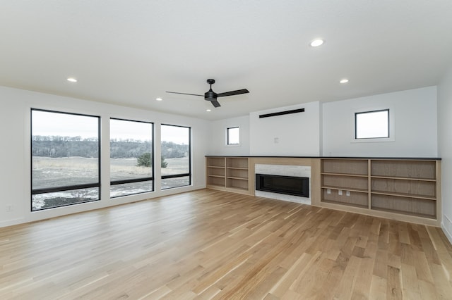 unfurnished living room with a healthy amount of sunlight, ceiling fan, and light hardwood / wood-style flooring