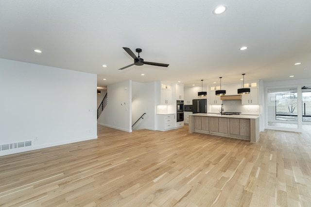 unfurnished living room featuring sink, light hardwood / wood-style flooring, and ceiling fan