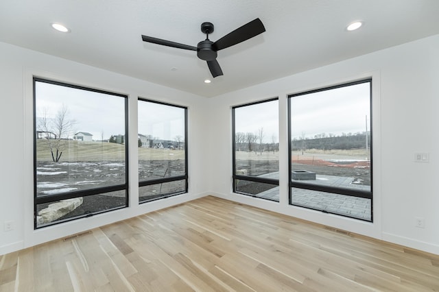 unfurnished room with ceiling fan, light hardwood / wood-style flooring, and a wealth of natural light