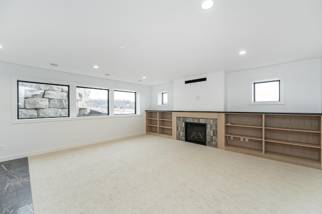 unfurnished living room featuring a wealth of natural light, a fireplace, and carpet flooring