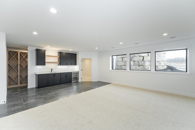 unfurnished living room featuring wine cooler, plenty of natural light, and sink