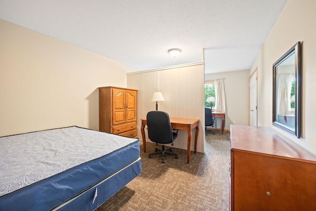 bedroom featuring dark carpet and a textured ceiling