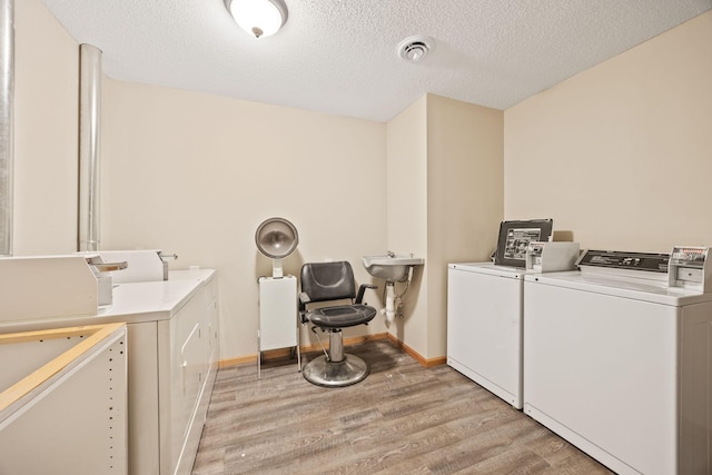 washroom with light hardwood / wood-style flooring, separate washer and dryer, and a textured ceiling