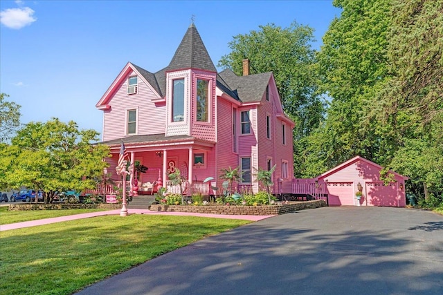 victorian home featuring an outbuilding, a front lawn, a garage, and a porch