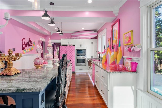 kitchen featuring white cabinets, stainless steel appliances, hardwood / wood-style flooring, and light stone countertops