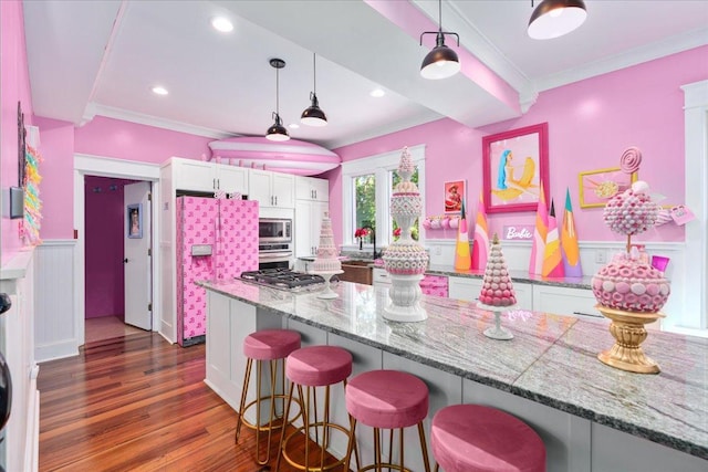 kitchen featuring dark wood-type flooring, stainless steel appliances, a kitchen bar, sink, and white cabinetry