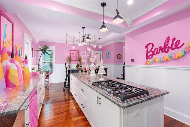 kitchen with stainless steel gas stovetop, white cabinets, hardwood / wood-style floors, stone counters, and decorative light fixtures