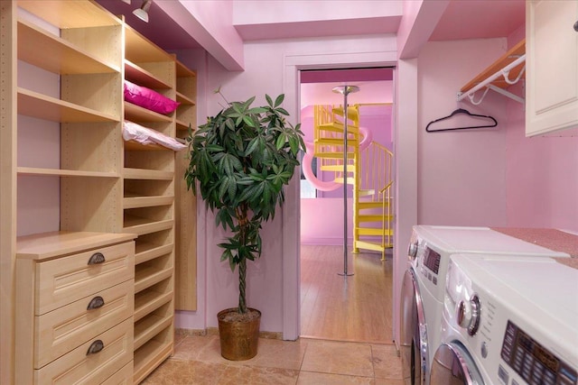 washroom with washer and dryer, light tile patterned floors, and cabinets