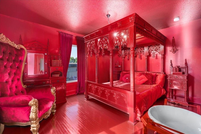 bedroom with a textured ceiling, hardwood / wood-style floors, and vaulted ceiling