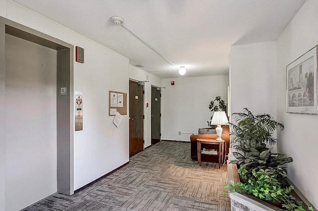 hall featuring dark colored carpet, a textured ceiling, and elevator