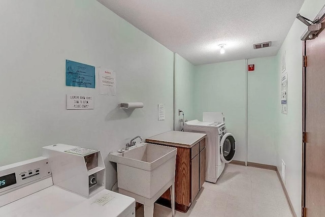 laundry area with separate washer and dryer, sink, cabinets, and a textured ceiling