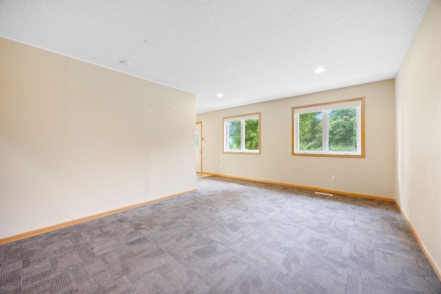 empty room with a textured ceiling and carpet flooring