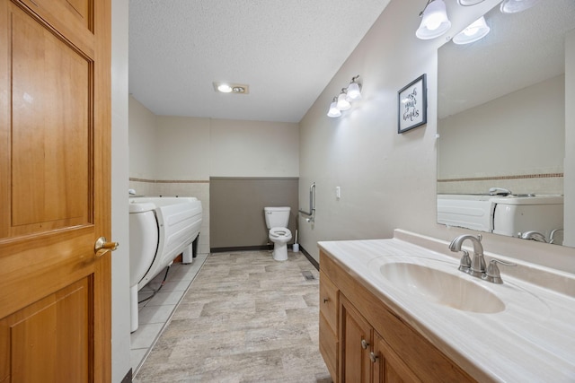 bathroom featuring tile patterned floors, vanity, a textured ceiling, and toilet