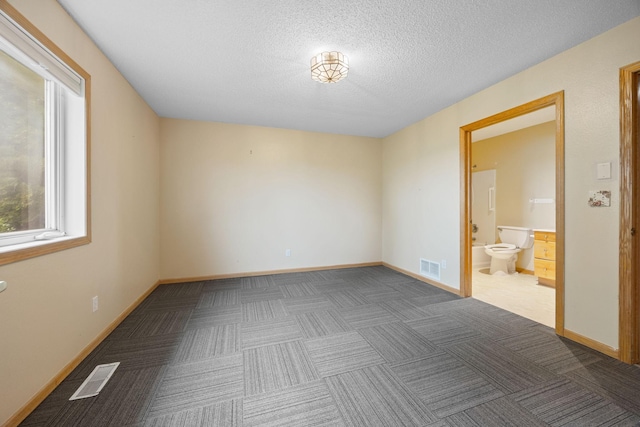 unfurnished bedroom with a textured ceiling and connected bathroom