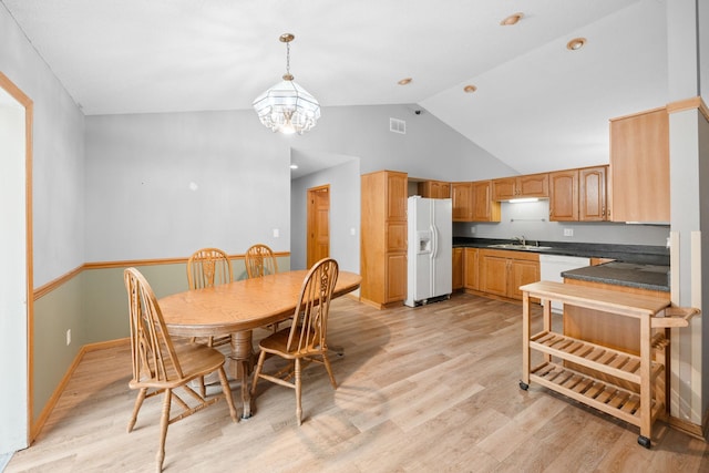 dining space featuring a notable chandelier, sink, high vaulted ceiling, and light hardwood / wood-style floors