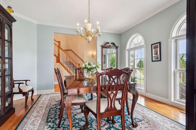 dining space with ornamental molding, light wood finished floors, baseboards, and an inviting chandelier