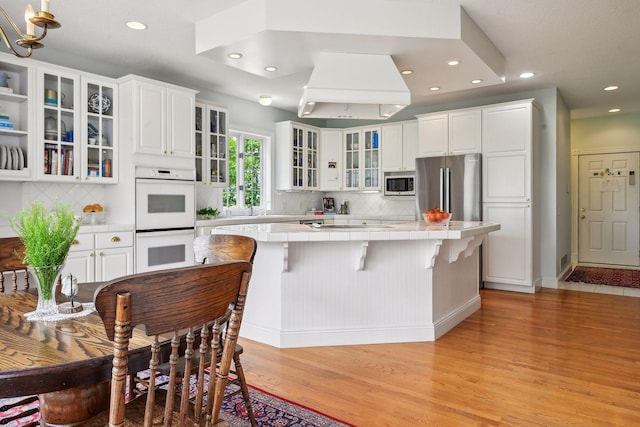 kitchen with white cabinets, appliances with stainless steel finishes, tile counters, and a center island