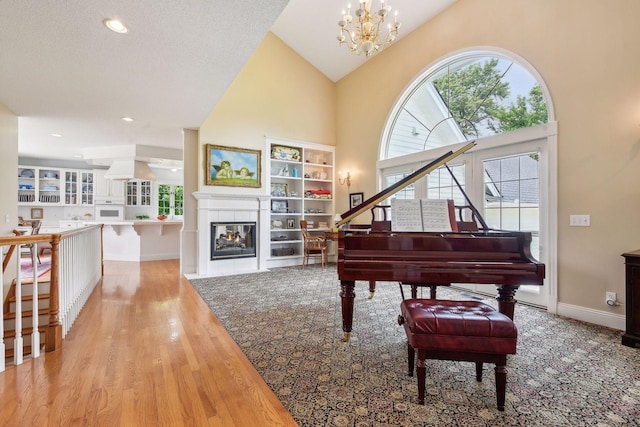 sitting room with high vaulted ceiling, a multi sided fireplace, light wood-style flooring, and baseboards