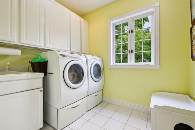 clothes washing area with washing machine and dryer, cabinet space, baseboards, and light tile patterned floors