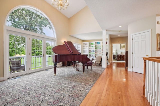 sitting room featuring built in features, a towering ceiling, wood finished floors, a notable chandelier, and recessed lighting