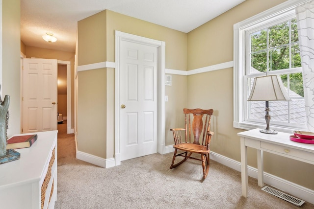 sitting room with light carpet, a textured ceiling, visible vents, and baseboards