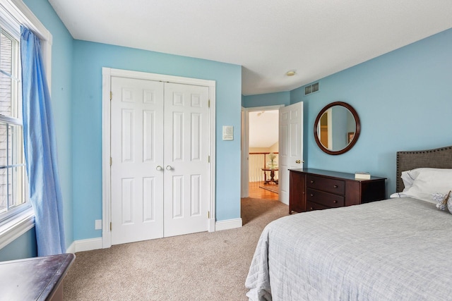 carpeted bedroom with a closet, visible vents, and baseboards