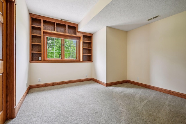 unfurnished room with carpet, visible vents, a textured ceiling, and baseboards