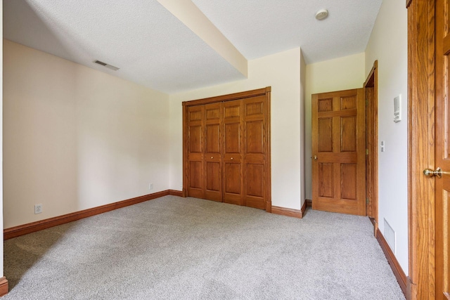 unfurnished bedroom with visible vents, carpet flooring, a textured ceiling, and baseboards