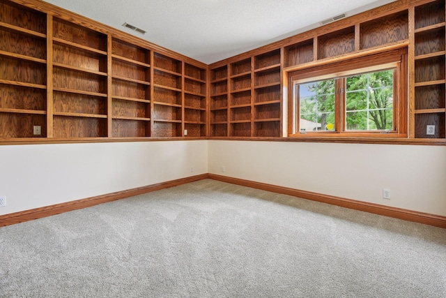 carpeted spare room featuring baseboards, visible vents, and a textured ceiling