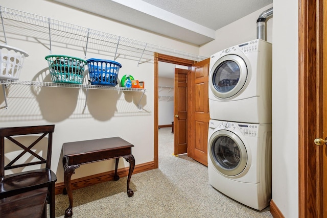 laundry area featuring stacked washer and clothes dryer, light carpet, a textured ceiling, laundry area, and baseboards