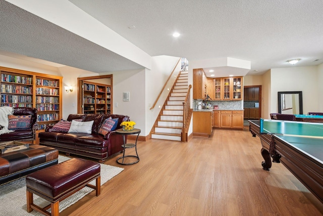 game room featuring light wood-type flooring, billiards, baseboards, and a textured ceiling