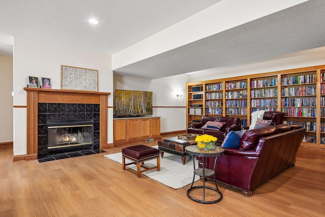 living room featuring a textured ceiling, a fireplace, wood finished floors, and baseboards