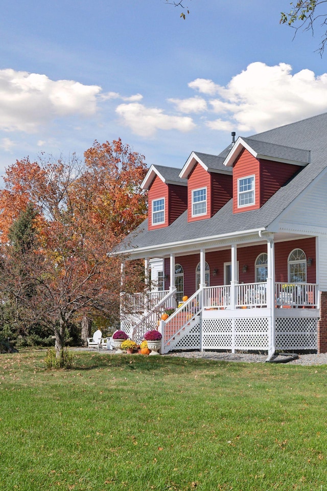 view of front of house featuring covered porch, a shingled roof, and a front yard