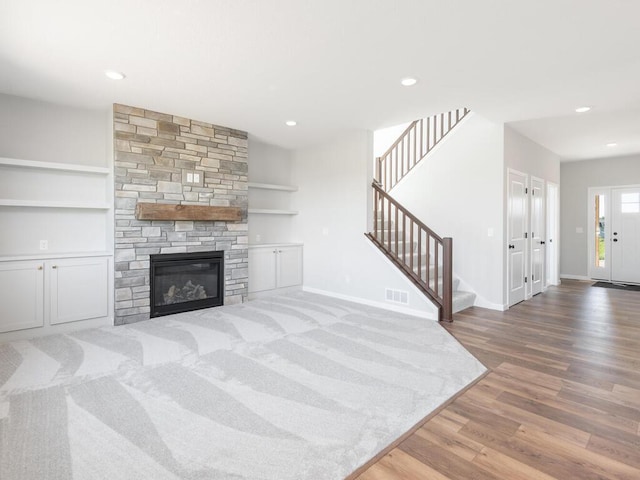 unfurnished living room featuring a stone fireplace and hardwood / wood-style flooring