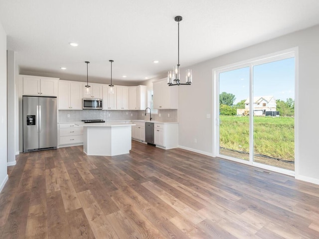 kitchen with hardwood / wood-style flooring, stainless steel appliances, decorative light fixtures, a chandelier, and white cabinets