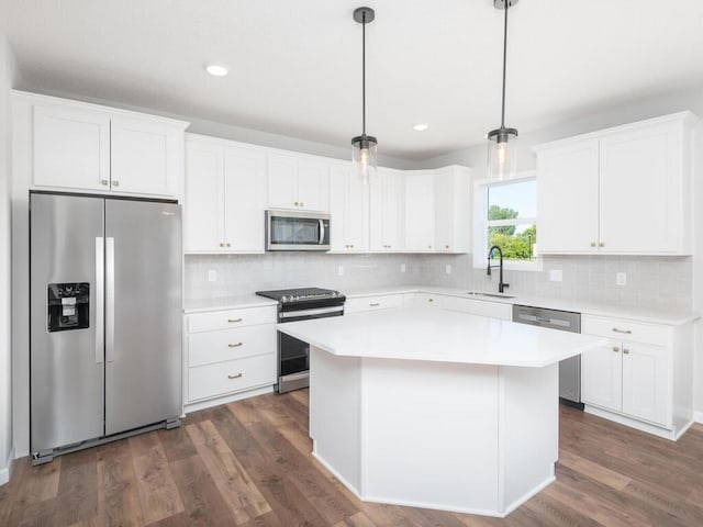 kitchen with hanging light fixtures, sink, a center island, white cabinetry, and appliances with stainless steel finishes