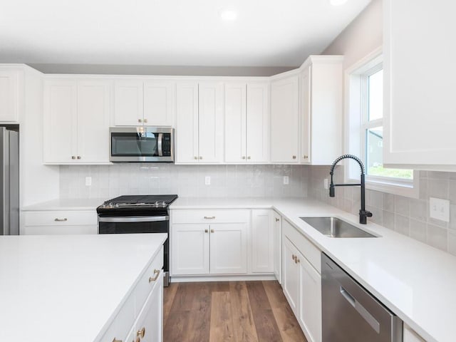 kitchen featuring white cabinets, backsplash, appliances with stainless steel finishes, dark hardwood / wood-style floors, and sink