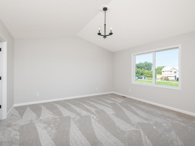 unfurnished room with lofted ceiling, a chandelier, and carpet flooring