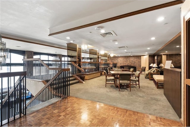 dining space featuring brick wall, a chandelier, a brick fireplace, and light parquet floors