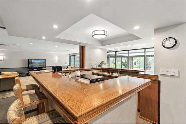 kitchen featuring sink, kitchen peninsula, a breakfast bar, and a tray ceiling