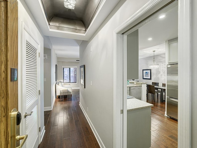 hallway with dark hardwood / wood-style flooring and a raised ceiling