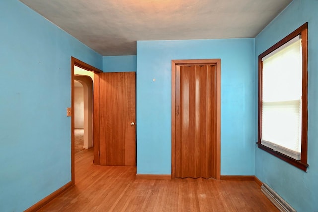 unfurnished bedroom with light hardwood / wood-style flooring and baseboard heating